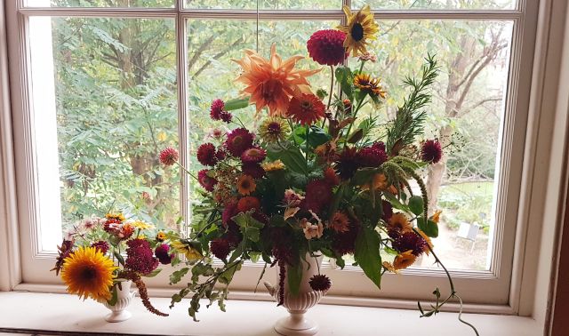 Umweltfreundliche Flowershow im Strawberry Hill House. Dunkelrotes und lachsfarbenes Bouquet in weißem Kelch 