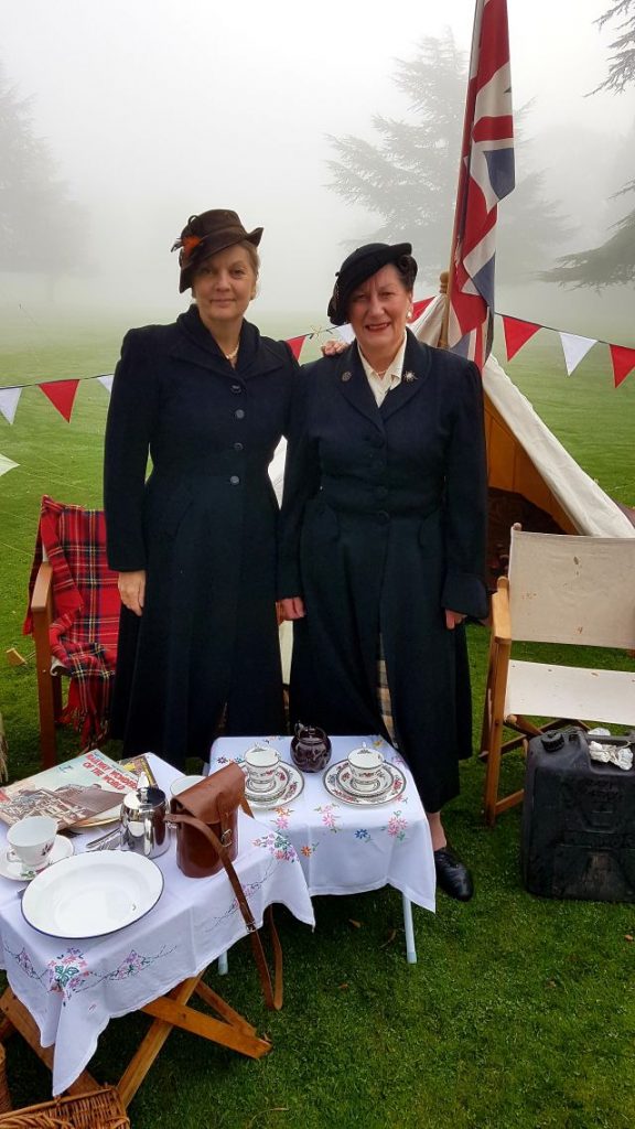 zwei damen im dunkelbaluen Kostüm und britische Flagge