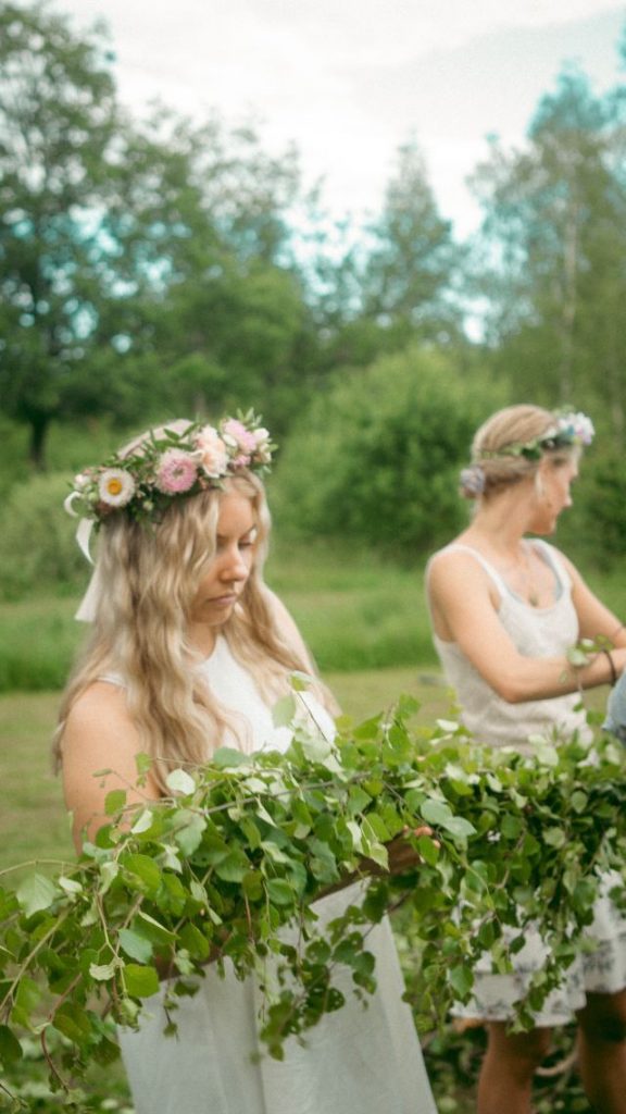 Blonde Mädchen mit Blumenkranz im Haar binden Efeuranke, 1. Mai in Großbritannien