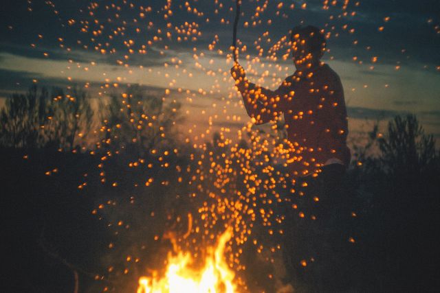 Mann tanzt mit Stock ums Feuer, Feuerfunken, 1. Mai, heidnische Bräuche