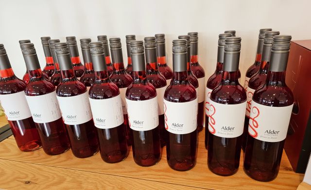 drei Reihen Flaschen Rotwein Rosé Alder Wein